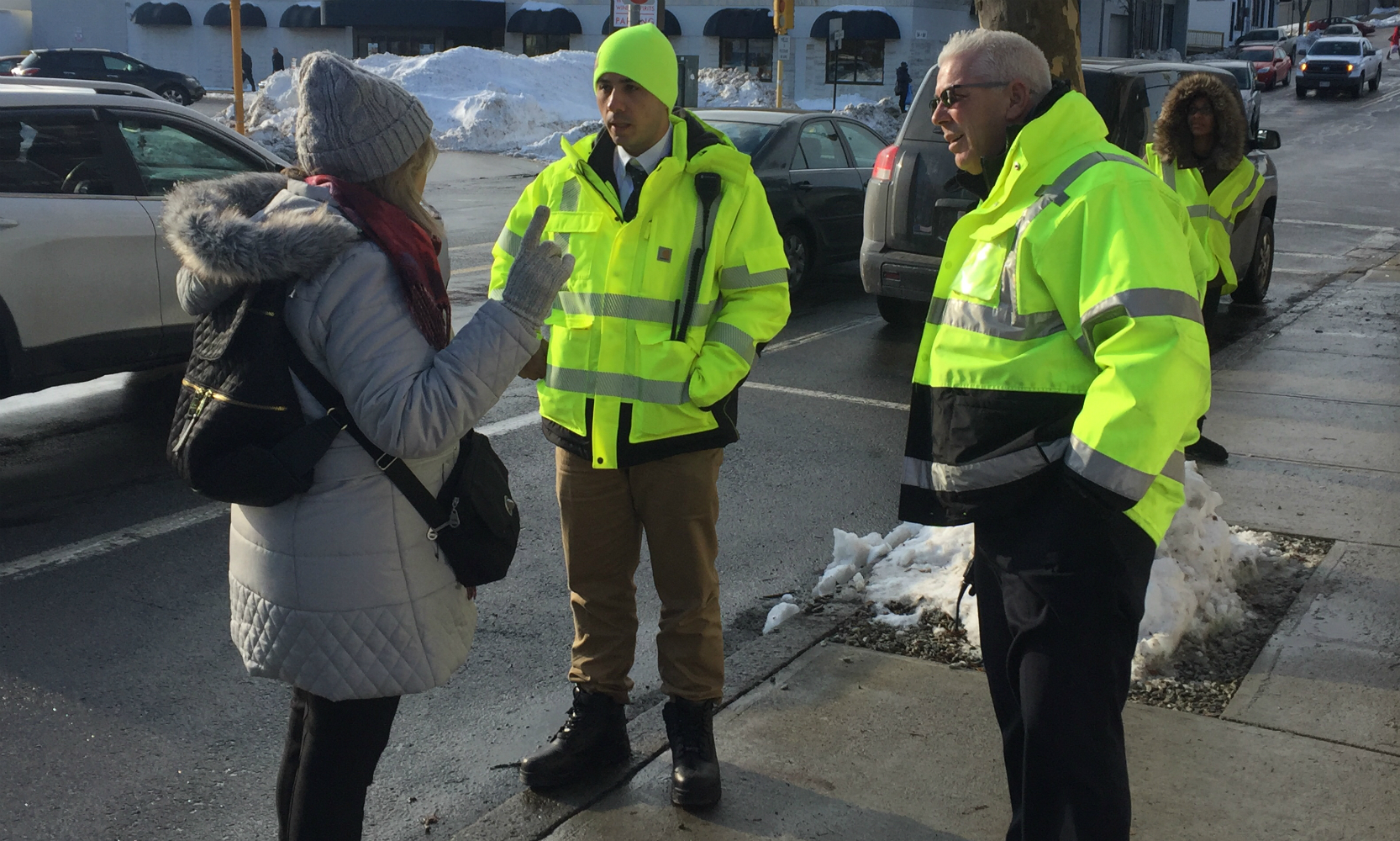 Two crewmen in neon jackets answer the question of a woman.