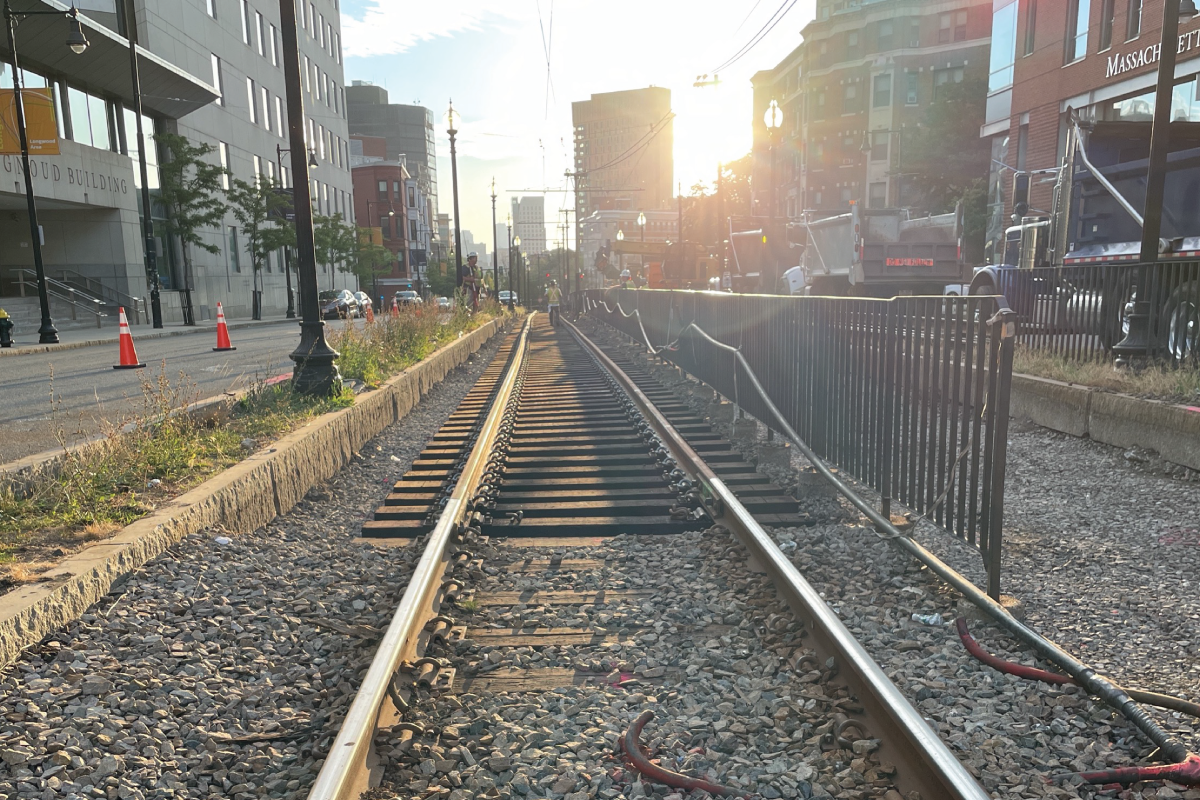 a photo of crew members standing on green line tracks with the boston skyline in the background 