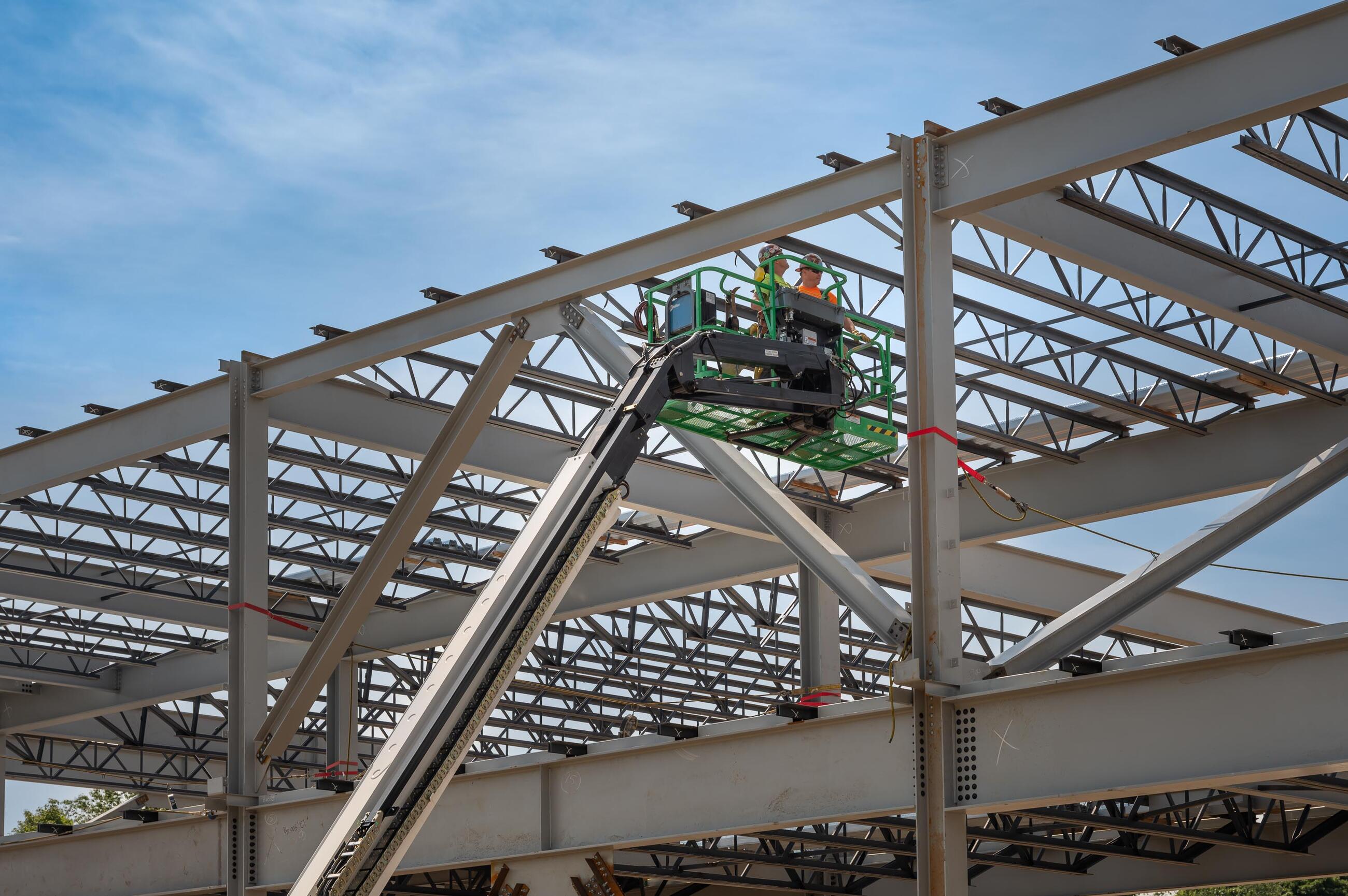 Construction workers on an aerial lift work on a new steel structure